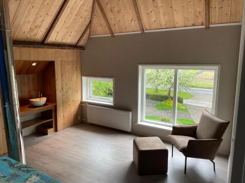 a living room with two windows and a chair at Appartement Elperhof 16A in Schoonloo
