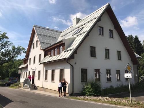 due persone in piedi di fronte a un edificio bianco di Horský apartmán s výhledem na Lysou horu a Rokytnice nad Jizerou