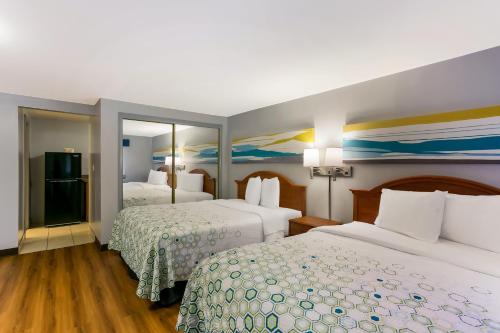 a hotel room with two beds and two mirrors at HomeTowne Studios by Red Roof Denver, PA in Denver