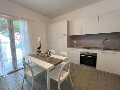 cocina con mesa, sillas y fregadero en Residenza Clelia Riccione en Riccione