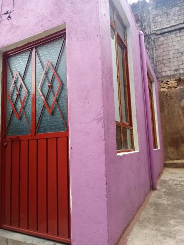a pink building with a red door and a window at 224 in Oaxaca City