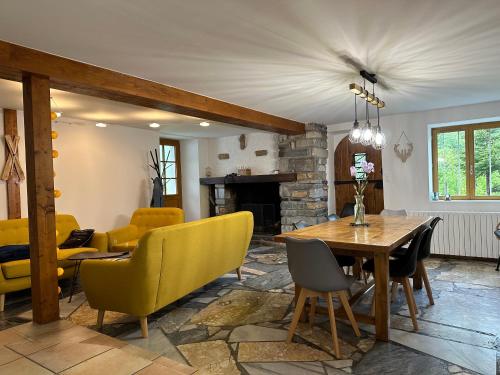 - un salon avec une table en bois et des chaises jaunes dans l'établissement La Bergerie Marie, à Saint-Aventin