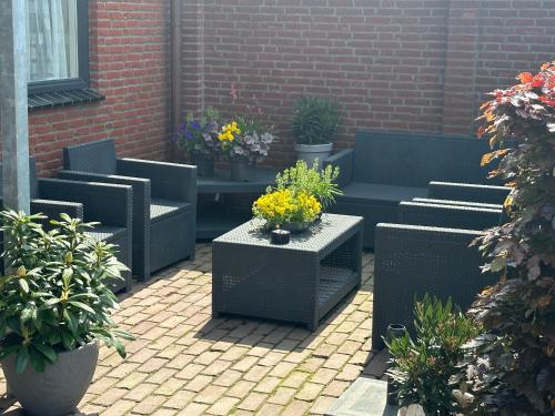 a patio with couches and potted plants and flowers at Bed&Breakfast de Hooimoat in Losser