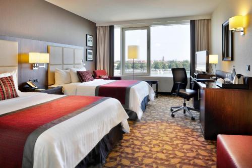 a hotel room with two beds and a desk at Courtyard by Marriott Hannover Maschsee in Hannover
