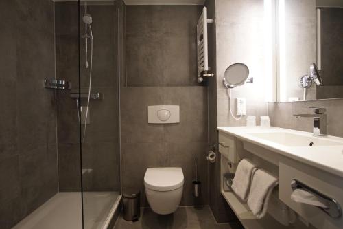a bathroom with a toilet and a sink and a shower at Courtyard by Marriott Hannover Maschsee in Hannover