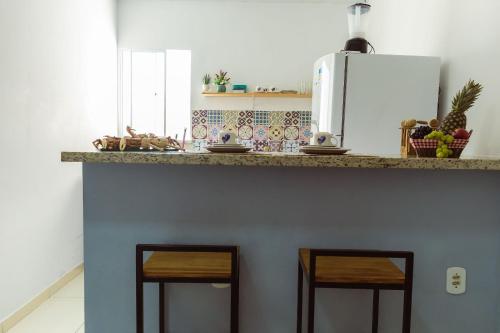 uma cozinha com um balcão com dois bancos por baixo em FLAT com 2 QUARTOS a 100m ORLA ATALAIA na TEMPORADA737 com PISCINA, CHURRASQUEIRA - Wi-Fi 180mbps e Cozinha em Aracaju