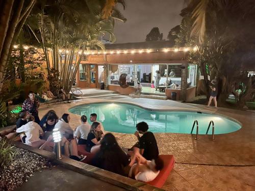 un grupo de personas sentadas alrededor de una piscina por la noche en Costa Rica Backpackers, en San José