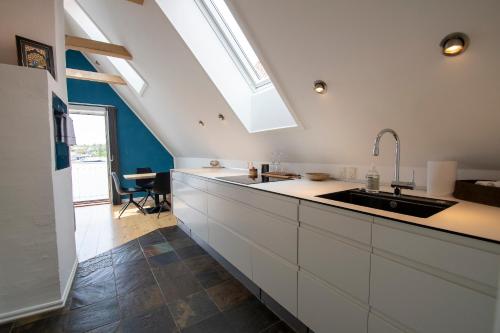 una cucina con armadi bianchi e lavandino di Sunset Penthouse a Sønderborg