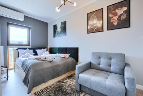 - une chambre avec un lit et une chaise dans l'établissement Apartament AREKA A16 Green Resort - klimatyzacja, basen, sauny, jacuzzi, siłownia, à Szklarska Poręba
