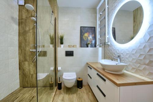 La salle de bains est pourvue d'un lavabo et d'une douche en verre. dans l'établissement Apartament AREKA A16 Green Resort - klimatyzacja, basen, sauny, jacuzzi, siłownia, à Szklarska Poręba