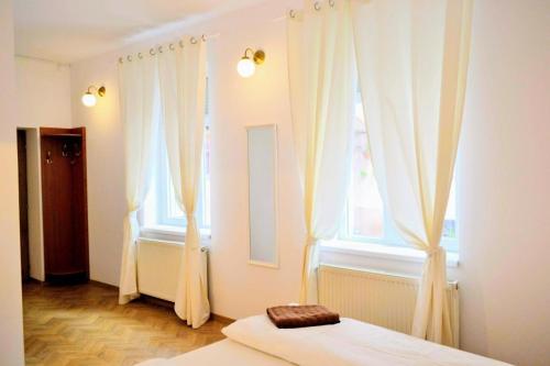 um quarto com cortinas brancas, uma cama e uma janela em Twins Boutique Korsy em Sibiu