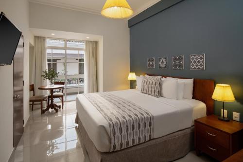 a bedroom with a large bed and a dining room at Hodelpa Caribe Colonial in Santo Domingo