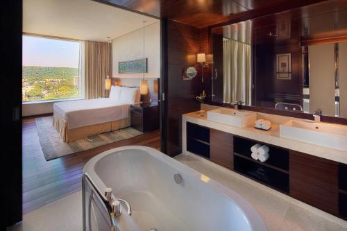 a bathroom with a tub and a bedroom with a bed at JW Marriott Pune in Pune