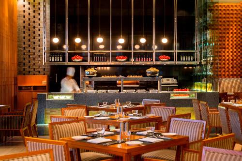 a restaurant with wooden tables and chairs and a chef in the background at JW Marriott Pune in Pune
