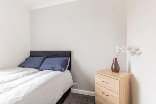 a bedroom with a bed and a wooden dresser at Memory Lane - beautifully renovated house close to motorway networks in Shevington
