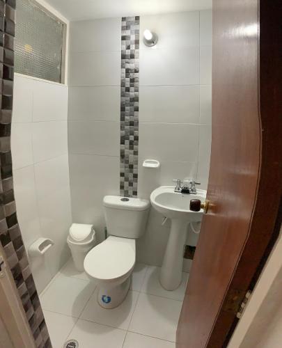 La salle de bains blanche est pourvue de toilettes et d'un lavabo. dans l'établissement CASA BLANCA, à Sogamoso