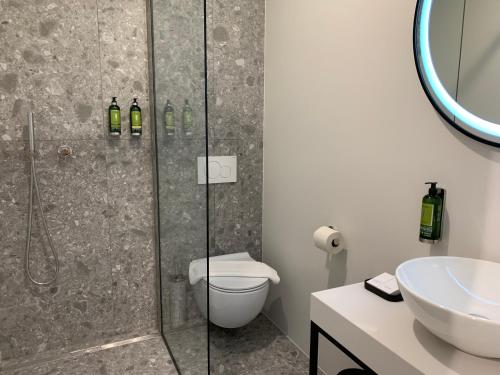 a bathroom with a shower and a toilet and a sink at Bloom Hotel in Ljubljana