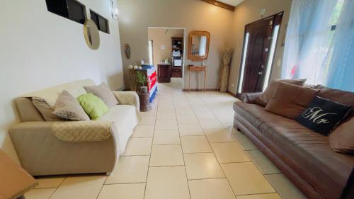 sala de estar con 2 sofás y suelo de baldosa. en Around Juan Santa María, en Alajuela