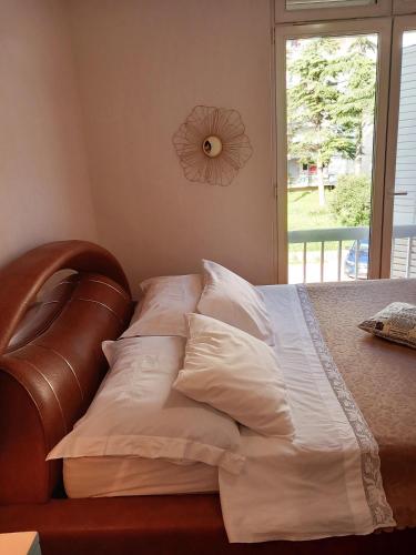 a bedroom with a bed with white pillows and a window at Apartment Navigator's lodging in Kotor