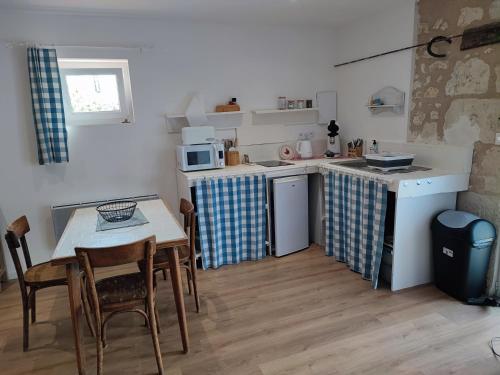une cuisine avec une table et une petite cuisine avec une table et des chaises dans l'établissement Le petit pré écolo, à Longué