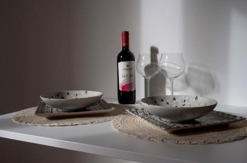 una botella de vino, dos tazones y una copa de vino en B&B Giulia, en Grammichele