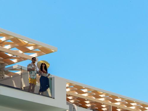 un homme et une femme debout sur le balcon d'une maison dans l'établissement Aliv stone suites & spa, à Agios Nikolaos