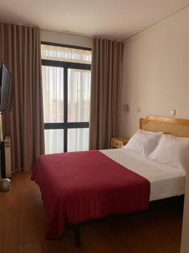 a bedroom with a bed with a red blanket and a window at Hotel Mar Azul in Espinho