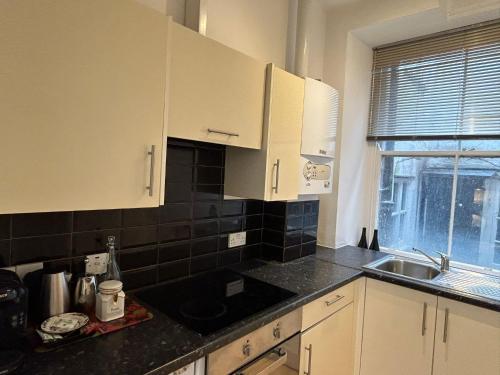 a kitchen with white cabinets and a sink and a window at John Street Apartments Flat 2 in Bristol