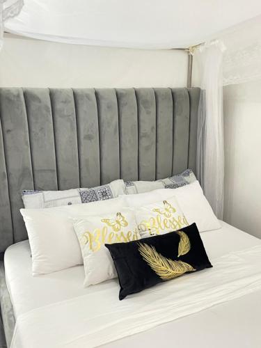 Cama blanca con cabecero gris y algunas almohadas en Unique apartment 2, en Mombasa
