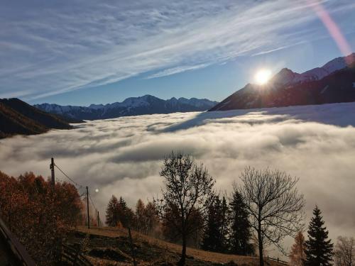 un mar de nubes en un valle con el sol saliendo sobre las montañas en Budamerhof, en Virgen