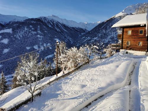 uma montanha coberta de neve com uma casa em cima dela em Budamerhof em Virgen