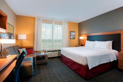 een hotelkamer met een groot bed en een bureau bij TownePlace Suites Orlando at FLAMINGO CROSSINGS® Town Center/Western Entrance in Orlando