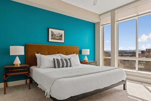 a blue bedroom with a bed and two windows at Kasa Union Station Denver in Denver