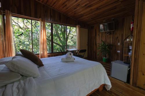 a bedroom with a white bed with a stuffed animal on it at The Green Tree Lodge in Monteverde Costa Rica