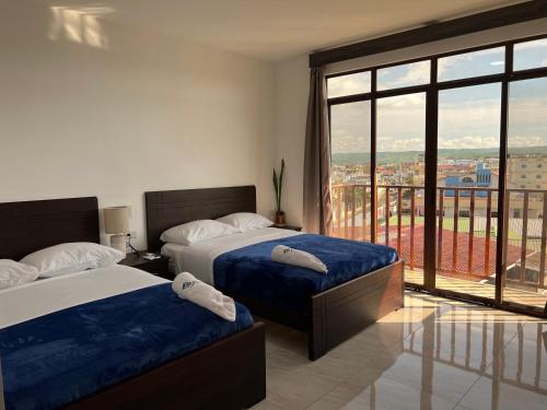 1 dormitorio con 2 camas y ventana grande en Katamar, en Manta