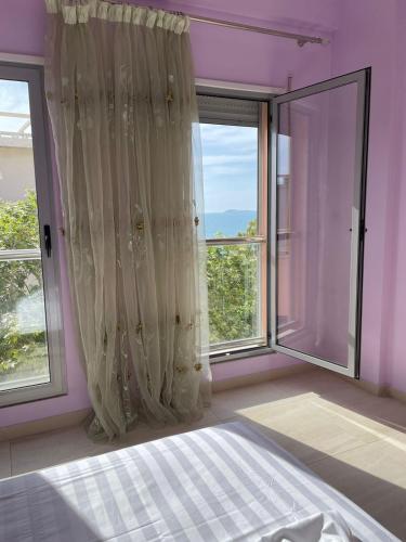 een slaapkamer met een bed en grote ramen bij Dakiba Apartment in Vlorë