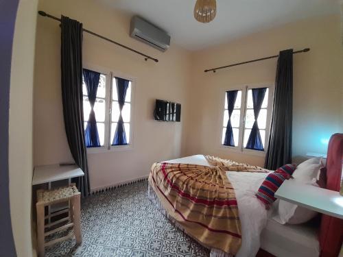 a bedroom with a bed and two windows at Hotel Mentaga in Taroudant