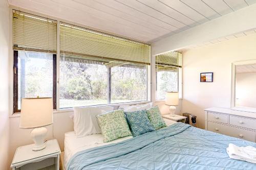 um quarto com uma cama com 2 candeeiros e 2 janelas em Bijha's View em Chilmark