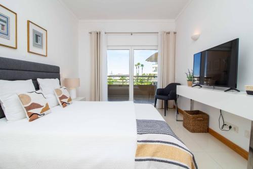 - une chambre avec un grand lit blanc et une télévision dans l'établissement Barracuda A14, à Albufeira