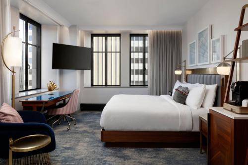 Cette chambre comprend un lit et un bureau. dans l'établissement Rand Tower Hotel, Minneapolis, a Tribute Portfolio Hotel, à Minneapolis