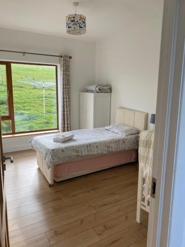 a bedroom with a bed and a large window at Coast Lodge - Family vacation in Mulranny