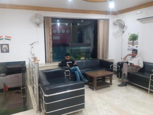 two men sitting on couches in a living room at Hotel Marina in New Delhi