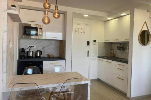 une cuisine avec des armoires blanches et une table et des chaises dans l'établissement Vue panoramique, plage à 100m, à Cannes