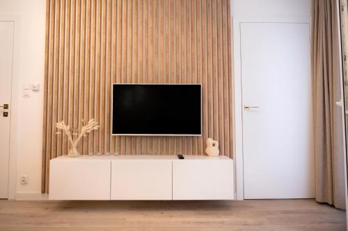 uma televisão em cima de um armário branco num quarto em Baltic Harmony - Easy-Rent Apartments em Pobierowo