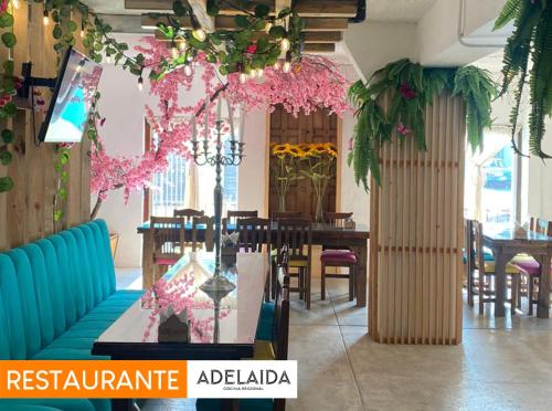 un restaurante con mesa, sillas y flores rosas en Hotel Pepe Pancho en San Cristóbal de Las Casas