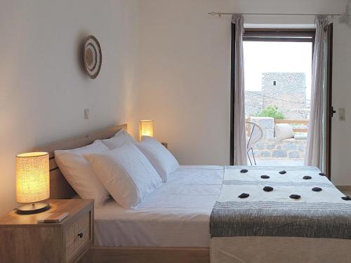 una camera da letto con un grande letto bianco e una finestra di kir-Yiannis stonehouse @Areopoli ad Areópolis