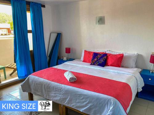 a bedroom with a king size bed with blue and red pillows at Hotel Pepe Pancho in San Cristóbal de Las Casas