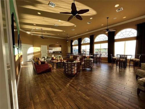 a living room with a ceiling fan and tables and chairs at BellaVida Orlando in Kissimmee