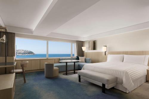 釜山にあるThe Westin Josun Busanのベッド付きのホテルルームで、海の景色を望めます。