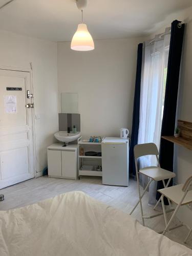 Cette chambre blanche dispose d'un lavabo, d'une table et de chaises. dans l'établissement Hotel La Défense, à Colombes